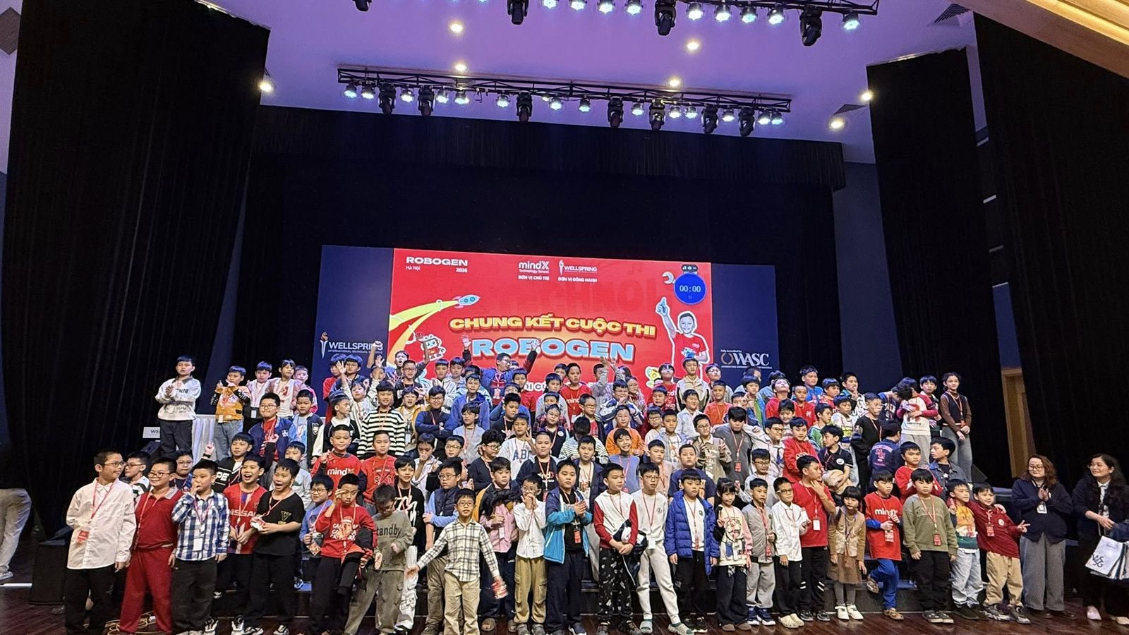 Học sinh và ban tổ chức chụp ảnh trên sân khấu tại chung kết cuộc thi ROBOGEN do MindX chủ trì
